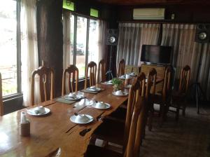 un lungo tavolo in legno con sedie e una televisione di Happy Resort Bandung a Ban Dung
