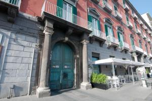 un bâtiment avec une porte verte, une table et un parasol dans l'établissement Relais Bijoux Napoli, à Naples