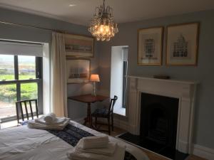 a bedroom with a bed and a fireplace and a chandelier at Farmhouse Boutique in Ballyheigue