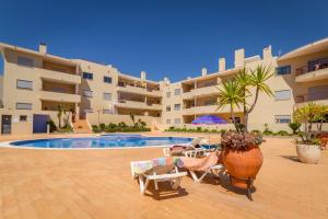 un complexe avec une piscine, des chaises et un bâtiment dans l'établissement The Hoffy Beach Apartment, à Lagos