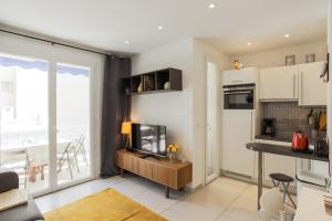 a living room with a television and a kitchen at Le Petit Magellan in Cannes