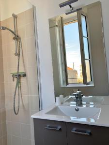 ein Bad mit einem Waschbecken und einer Dusche mit einem Spiegel in der Unterkunft Le Rayon de Soleil in Châtelaillon-Plage