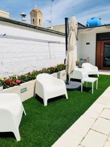 a patio with white chairs and an umbrella and grass at Truly Apulia in Bari