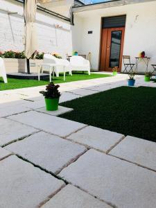 a patio with white tables and chairs and grass at Truly Apulia in Bari