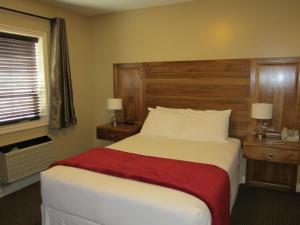 a bedroom with a large bed with a wooden headboard at Reynolds Hotel in Lillooet