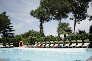 una piscina con tumbonas y árboles en Villaggio Mithos en Misano Adriatico