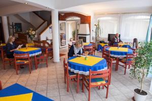 a group of people sitting at tables in a restaurant at Villa Mediterran in Hévíz