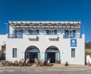 biały budynek ze stołami i krzesłami przed nim w obiekcie Anesis Hotel w mieście Agía Pelagía Kithira