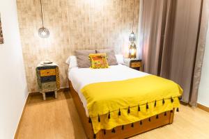 Triana Luxury Home في إشبيلية: غرفة نوم بسرير وبطانية صفراء