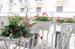 uma varanda com flores e plantas em cadeiras brancas em Relais Bijoux Napoli em Nápoles
