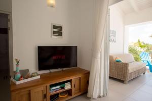 a living room with a flat screen tv on a wooden entertainment center at Appartement Barracuda in Kralendijk