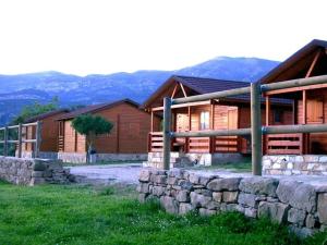 a log cabin with a stone wall next to a house at Camping Cañones de Guara y Formiga in Panzano