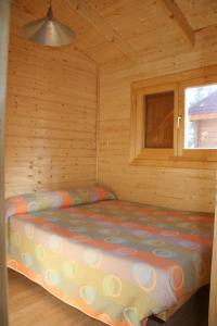 Ce lit se trouve dans une cabane en rondins dotée d'une fenêtre. dans l'établissement Camping Cañones de Guara y Formiga, à Panzano