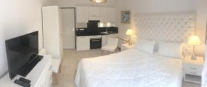 a bedroom with a white bed and a television at Villa Louise-Rose in Villeneuve-Loubet