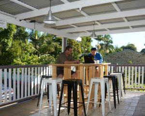 deux hommes assis à une table avec un ordinateur portable dans l'établissement Gonow Family Backpackers Hostel, à Brisbane