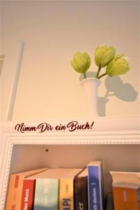 a shelf with books and a vase of flowers on it at Ferienwohnung Familie Anker - toll für Groß und Klein! in Hohwacht