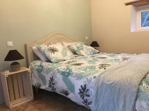a bedroom with a bed with a blue and white comforter at gite le cabanon in Réauville +22 photos