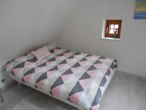 ein kleines Schlafzimmer mit einem Bett mit einer rosa und weißen Bettdecke in der Unterkunft Gîte l'Authentique avec spa en option in Orschwiller