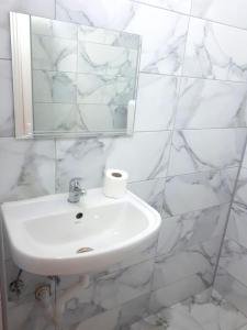 a white bathroom with a sink and a mirror at Edelweiss Hostel in Štip