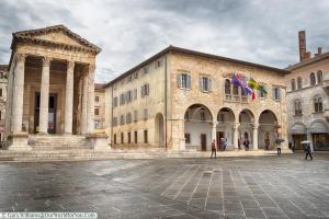 a large stone building with flags in a courtyard at Apartment Dada in Pula