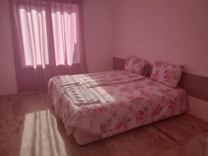 ein Schlafzimmer mit einem Bett mit einer rosa Decke in der Unterkunft Апартамент Нощувки Шумен in Schumen
