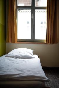 an unmade bed in a room with a window at Backpackers St. Pauli in Hamburg