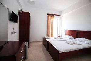 a hotel room with two beds and a television at Hotel Afrodite in Dhërmi