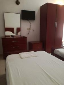 a bedroom with a bed with a dresser and a mirror at Hotel Afrodite in Dhërmi