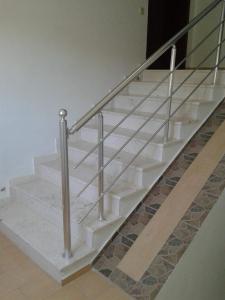 a staircase with a metal handrail and white stairs at Hotel Afrodite in Dhërmi