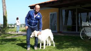 a man is standing next to a white dog at La Fattoria di Tirrenia in Tirrenia