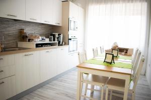 a kitchen with white cabinets and a wooden table with chairs at B&b '900 in Foggia