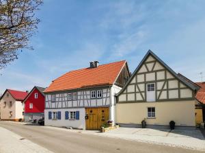 ein weißes Gebäude mit orangefarbenem Dach und einem roten Haus in der Unterkunft Ferienhaus am Eisgraben in Hausen