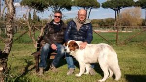 two men sitting on a bench with a dog at La Fattoria di Tirrenia in Tirrenia