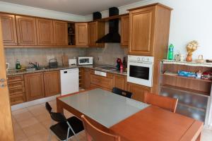 a kitchen with wooden cabinets and a table with chairs at Casa dos Cabecinhos in Oliveira do Hospital