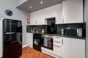 a kitchen with white cabinets and a black refrigerator at No 10 - by StayDunfermline in Dunfermline
