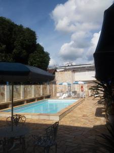 a swimming pool with a table and chairs and an umbrella at Apart Hotel em Caxambu207 in Caxambu