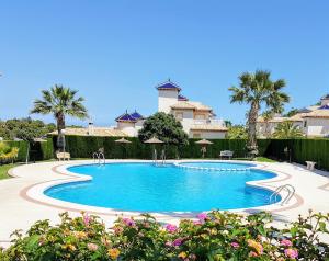 a swimming pool in front of a house with palm trees at Aalia villa in Villacosta