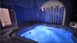 a jacuzzi tub in a room with a window at AMO Folegandros in Karavostasi