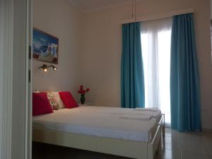 a bedroom with a bed with blue curtains and a window at Meletis Studios in Parikia