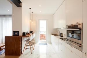 a kitchen with white cabinets and a wooden counter at CityStudios in Luxembourg