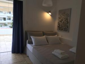 Bett mit weißen Kissen in einem Zimmer mit Fenster in der Unterkunft Bay watch Apartment close to the airport at PORTO RAFTI in Porto Rafti