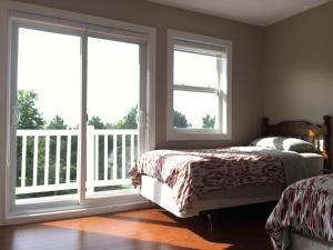 a bedroom with two windows and a bed and a balcony at Seaview White House in Stratford
