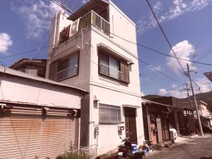 un edificio blanco con balcón en la parte superior en 冨の露～とみのつゆ～ en Setouchi