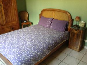 een bed met paarse lakens en een houten hoofdeinde bij Croix Blanche in Cellieu