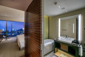 a bathroom with a tub and a sink and a bedroom at New World Guiyang Hotel in Guiyang