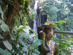 a statue in front of a waterfall in a forest at Atres Villa in Munduk