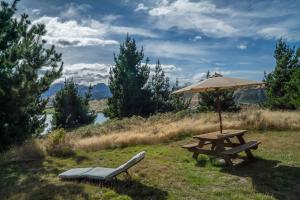 une table de pique-nique, un parasol et un banc dans l'établissement Mt Gold Glamping, à Wanaka
