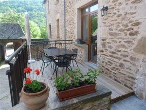 a balcony with a table and a table and flowers at gite Oustal in Belcastel