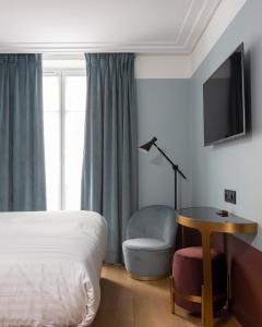 a bedroom with a bed and a chair and a tv at Hôtel Parisianer in Paris