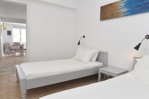 ein weißes Zimmer mit 2 Betten und einem Tisch in der Unterkunft VILLA PETROS SEA SUITE in Megas Gialos - Nites